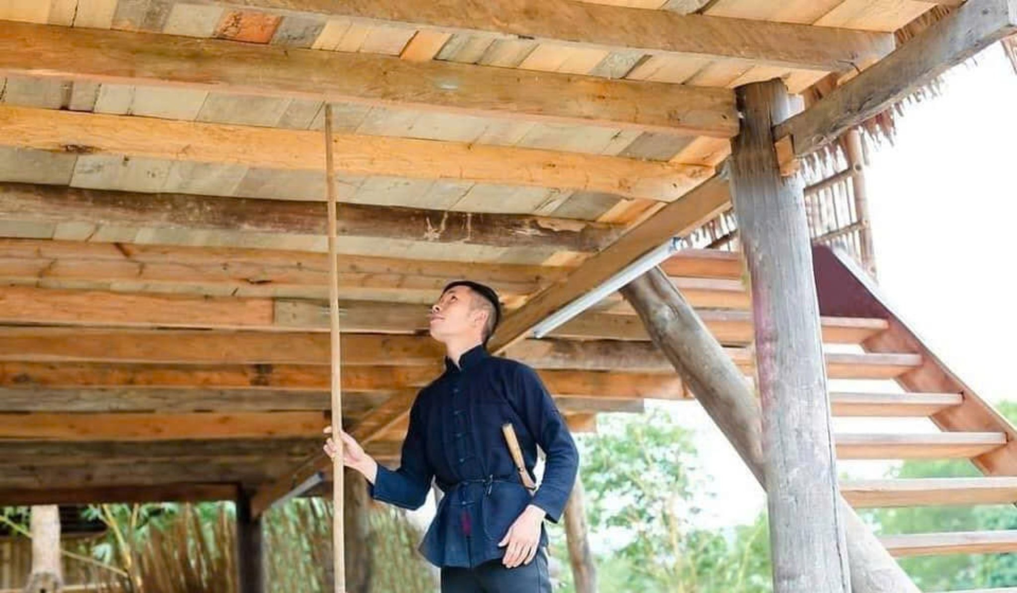 Chàng trai dùng cây gậy gõ hoặc chọc lên sàn nhà nơi cô gái đang nằm ngủ